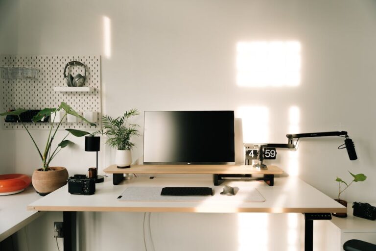 A clean and minimalist home office setup with plants, monitor, and microphone.