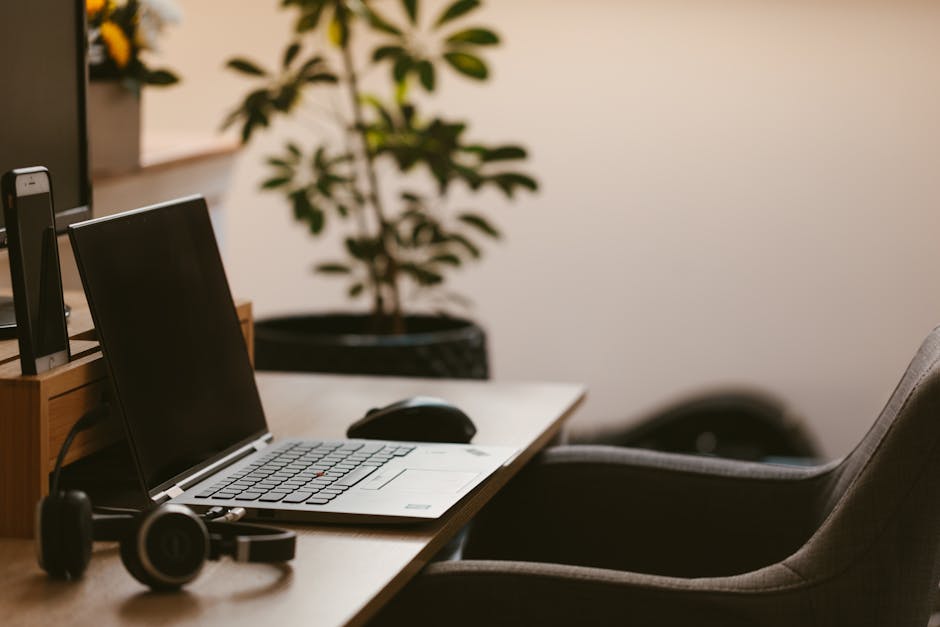 A cozy home office workspace with a laptop, headphones, and a plant. Ideal for remote work.